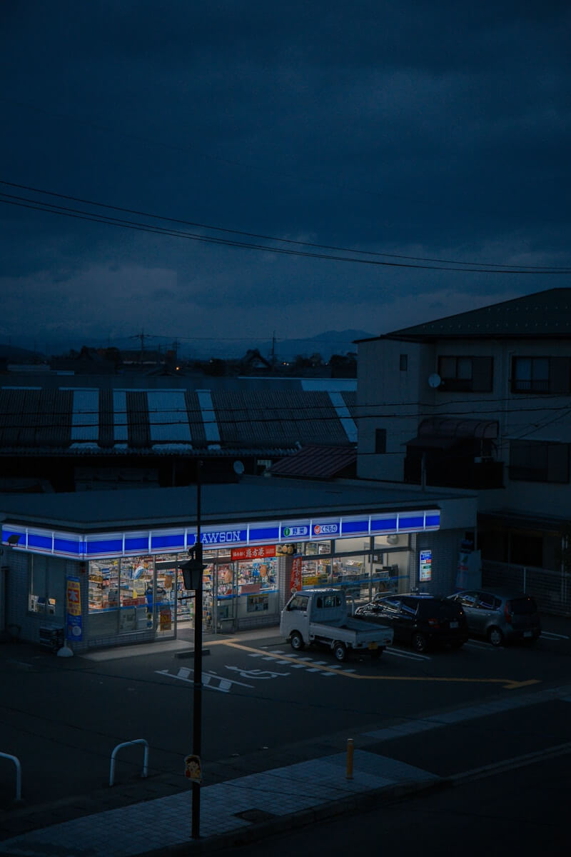 a gas station at night with cars parked in front of it